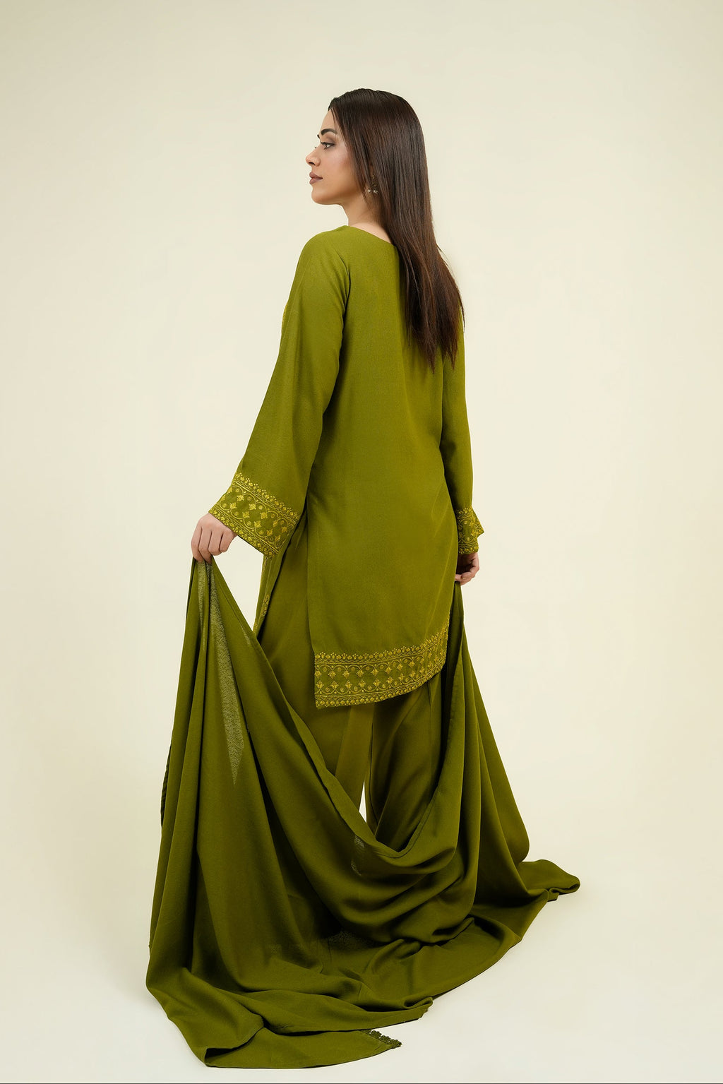 Woman wearing a green traditional outfit with a plain background