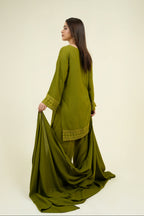 Woman wearing a green traditional outfit with a plain background