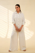 Woman wearing a white outfit standing against a beige background