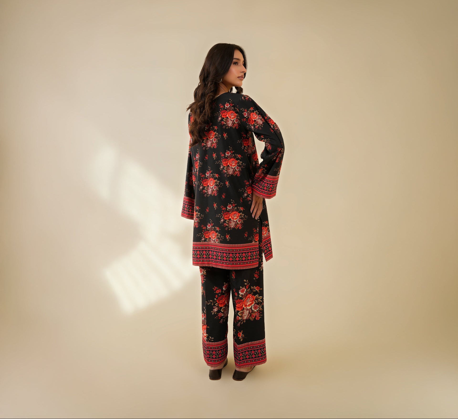 Woman wearing a black floral outfit on a beige background