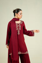 Woman wearing a burgundy traditional outfit with intricate lace details on a beige background